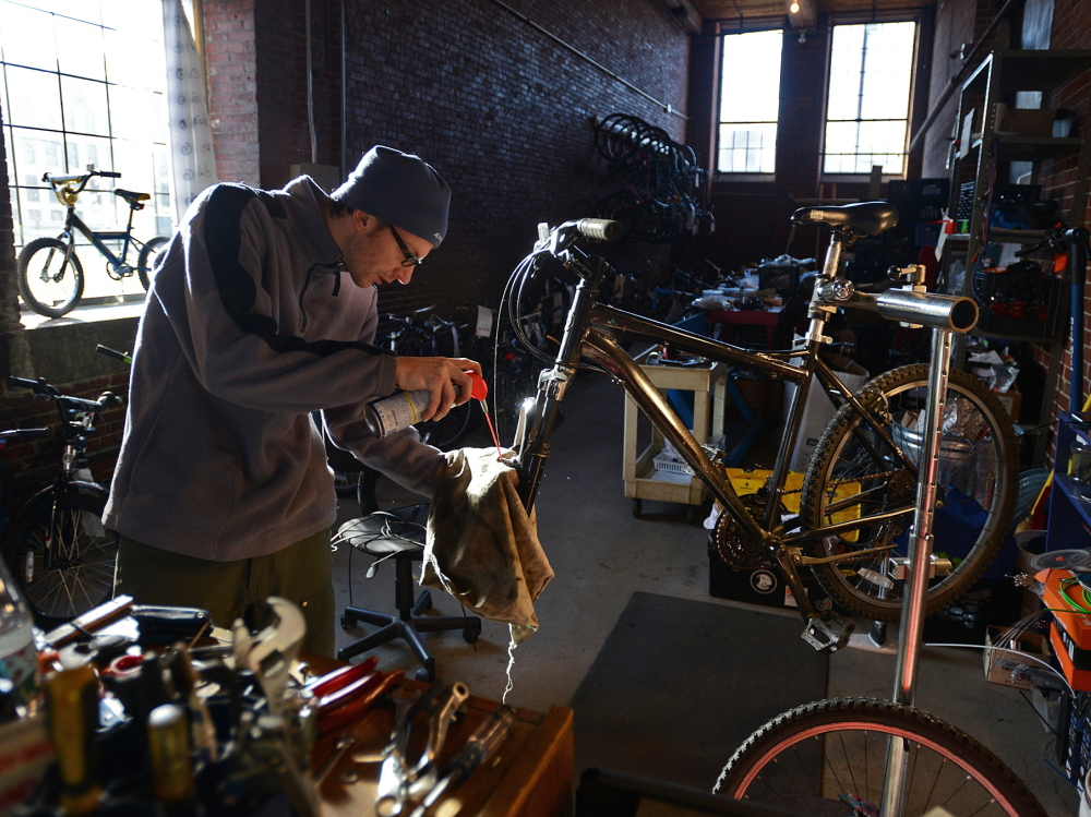 Karl Borne works on a bicycle at the Merrimack Valley YMCA’s BiciCocina, or Bike Kitchen, in Lawrence, Mass. 