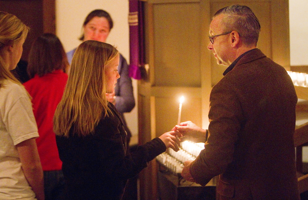 Lucy Hartley of South Portland takes a candle from usher Philip Hamilton at St. Alban’s Episcopal Church in Cape Elizabeth during a Celtic Eventide service on Dec. 7. The church’s pastor hopes to attract faithful Christians as well as fallen-away believers and those who’ve never attended church.