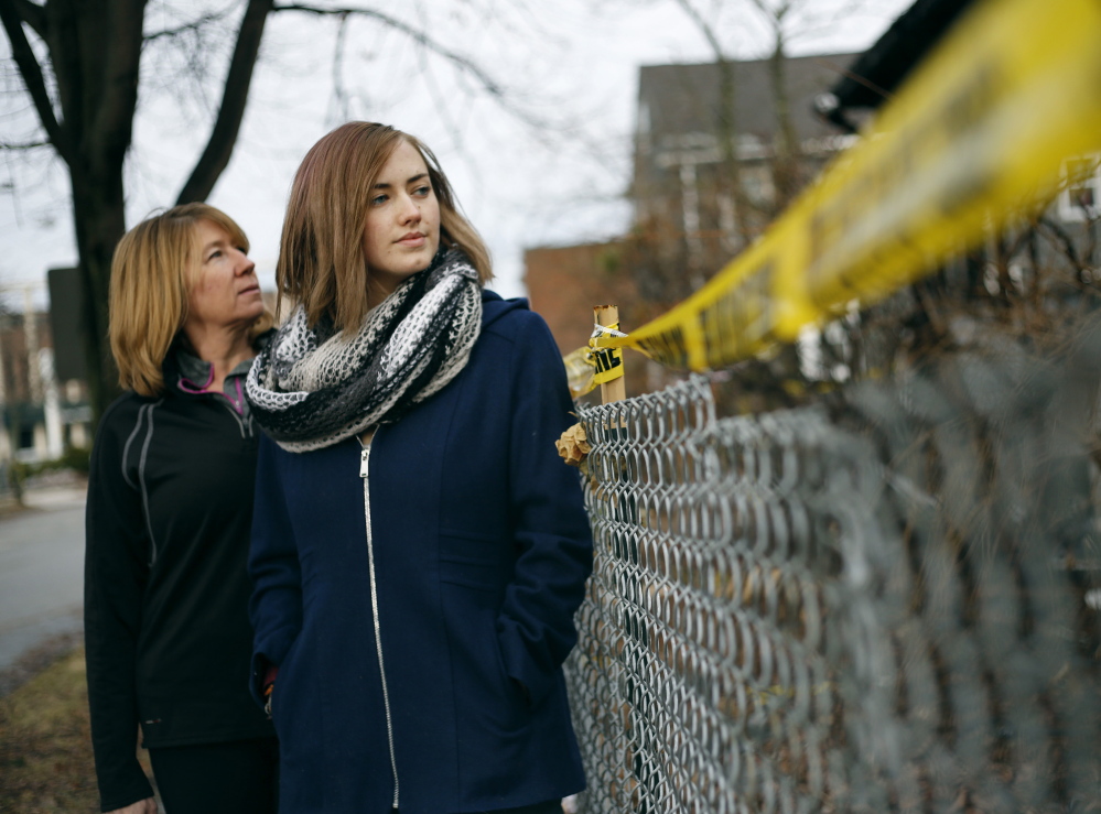 Catherine Wilson, left, and Grace Damon look over police barrier tape at the burned building at 20-24 Noyes St. in Portland. Damon, 23, who knew two of the fire victims, said that trying to form a tenant union to defend renters’ rights is “I guess my way of grieving.”