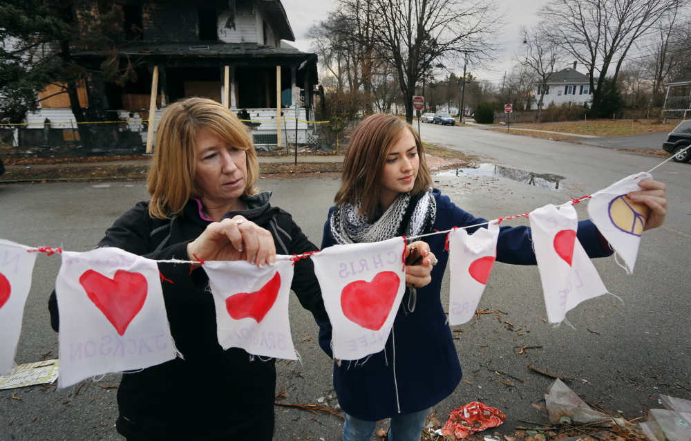 Catherine Wilson, left, and Grace Damon examine items left at a memorial across the street from the remains of a Noyes Street duplex that burned Nov. 1, killing six people. Wilson and Damon are organizing a group to defend the rights of Portland tenants.