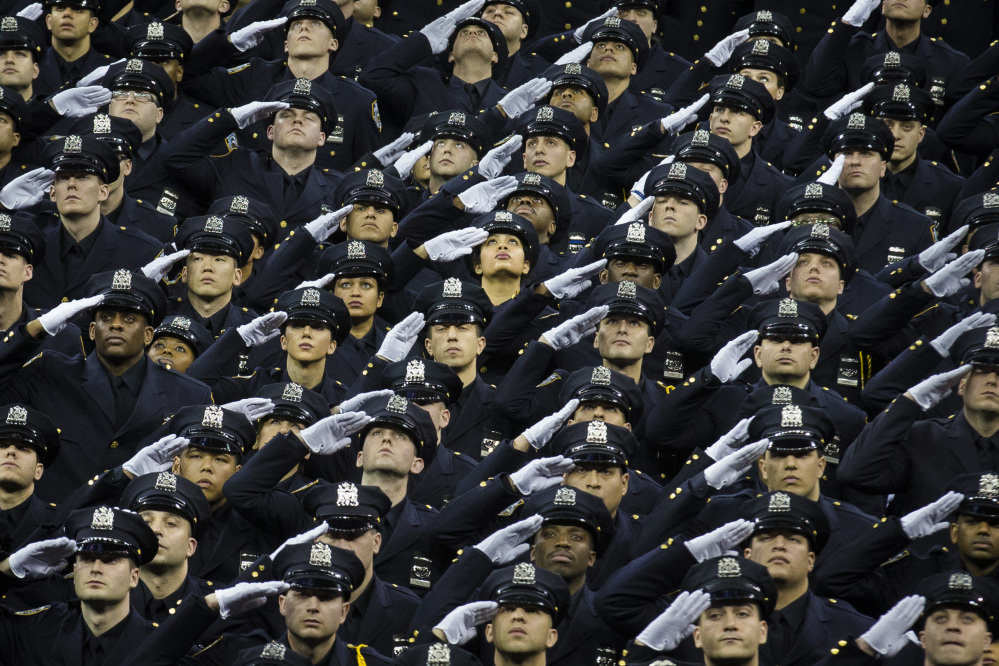 New officers salute their deceased comrades Rafael Ramos and Wenjian Liu during a New York Police Academy graduation ceremony on Monday. Nearly 900 officers were sworn in amid boos and heckles at New York’s mayor.
