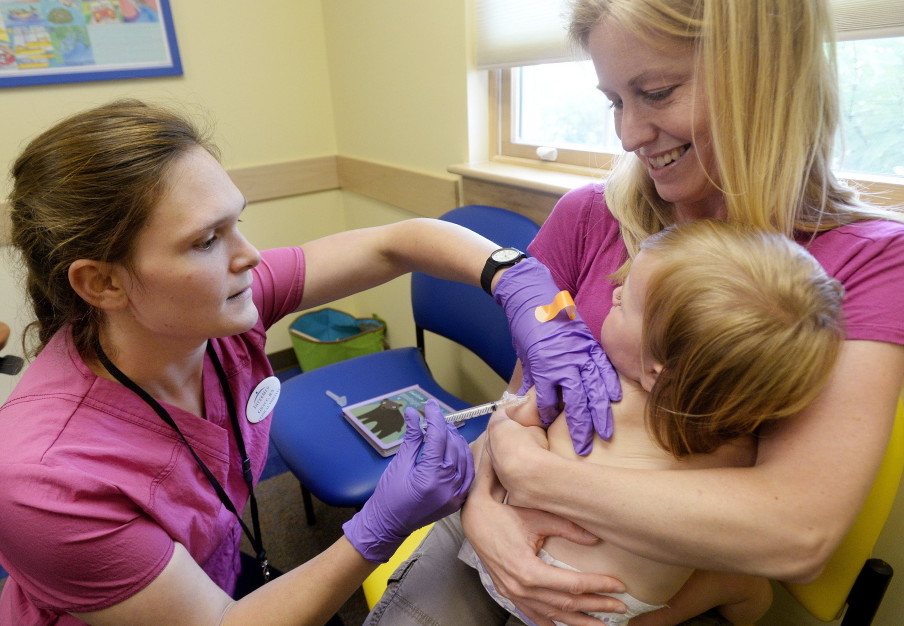 Amber Dugan of Durham holds Tessa as she gets a vaccination from Grace Montgomery at InterMed in Yarmouth. A new bill calls for parents who want to opt out of child immunizations for philosophic reasons to first consult with a primary care professional.