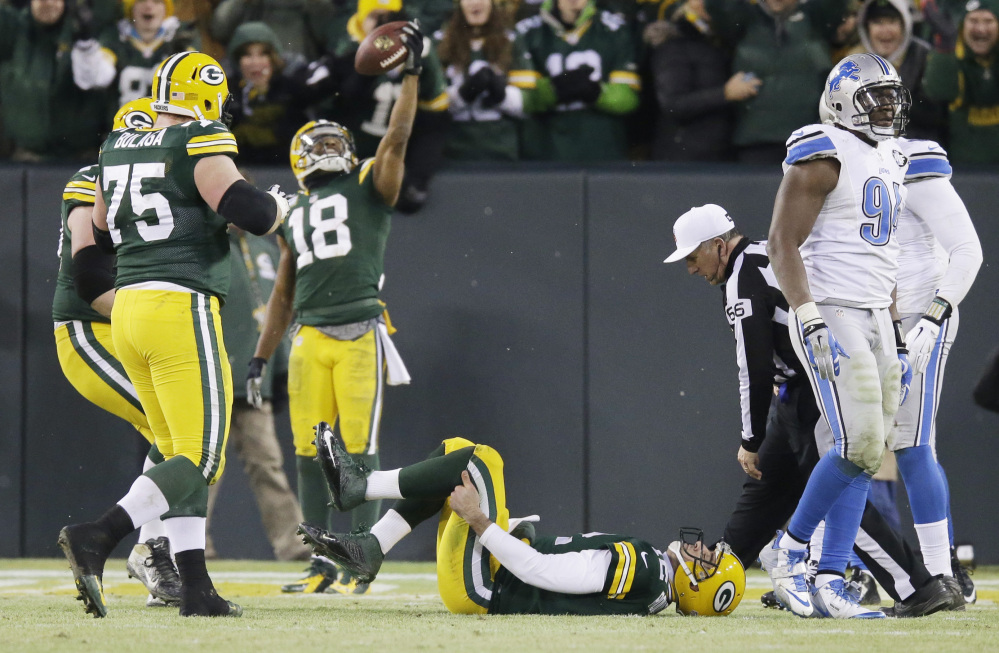 Packers quarterback Aaron Rodgers holds his leg as Randall Cobb celebrates a touchdown catch during the first half of Sunday’s game against the Detroit Lions. Rodgers left the game on a cart, but returned to play in the second half of Green Bay’s win.