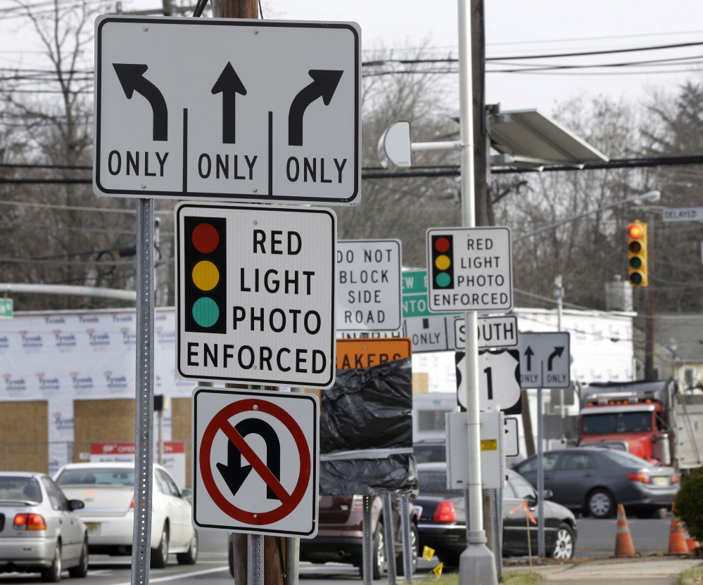 Traffic passes a photo enforcement sign below a red-light camera in Lawrence Township, N.J. 