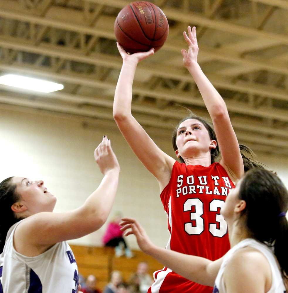 South Portland’s Maddie Hasson takes a shot over Amanda Brett and Cierra Burnham of Deering in Tuesday night’s SMAA girls’ basketball game at Portland. Deering rallied for a 59-52 win in overtime.