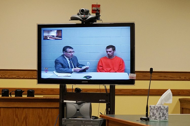 Shane Jones, right, appears by video link in Springvale District Court, seated beside attorney Scott Houde at the York County Jail, to face charges related to his mother's death. 
