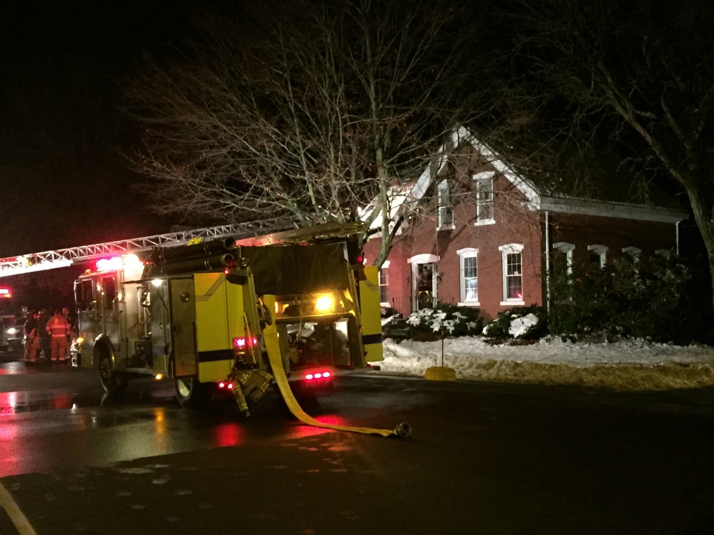 A firetruck sits outside the 251-year-old home damaged by fire late Sunday on East Bridge Street in Westbrook. The fire apparently started around a wood stove’s exhaust piping. Kevin Miller/Staff Writer