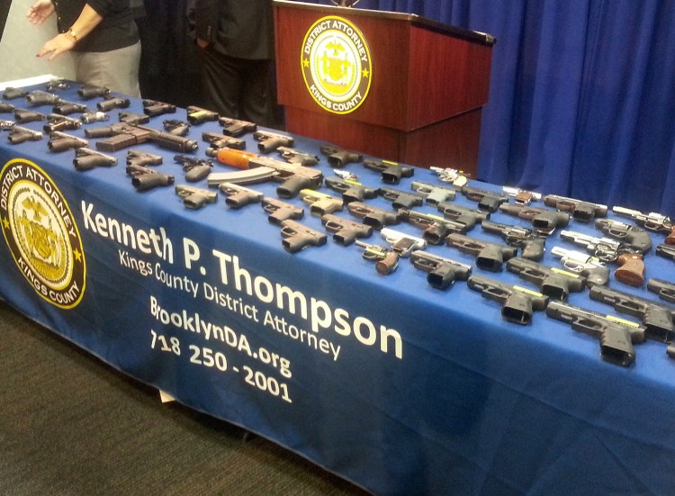 In this photo provided by the Brooklyn District Attorney's Office, a collection of handguns and two assault rifles fill a table during a news conference Tuesday. Investigators in New York arrested former Delta Airlines employee Mark Quentin Henry on Dec. 10 and charged him with transporting 153 guns on 17 commercial flights flights between Atlanta and New York.