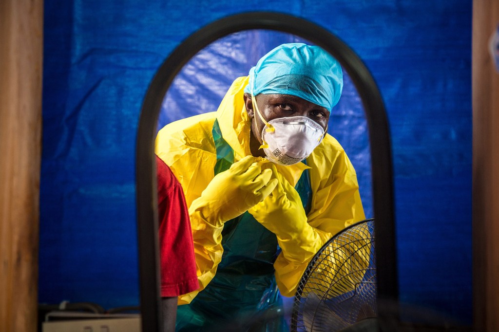 A health care worker dons protective gear before entering an Ebola treatment center in Freetown, Sierra Leone, in October. In a letter published online Wednesday by the New England Journal of Medicine, doctors report that the Ebola death rate appears to have fallen, even though there are no specific medicines or vaccines to fight the virus.