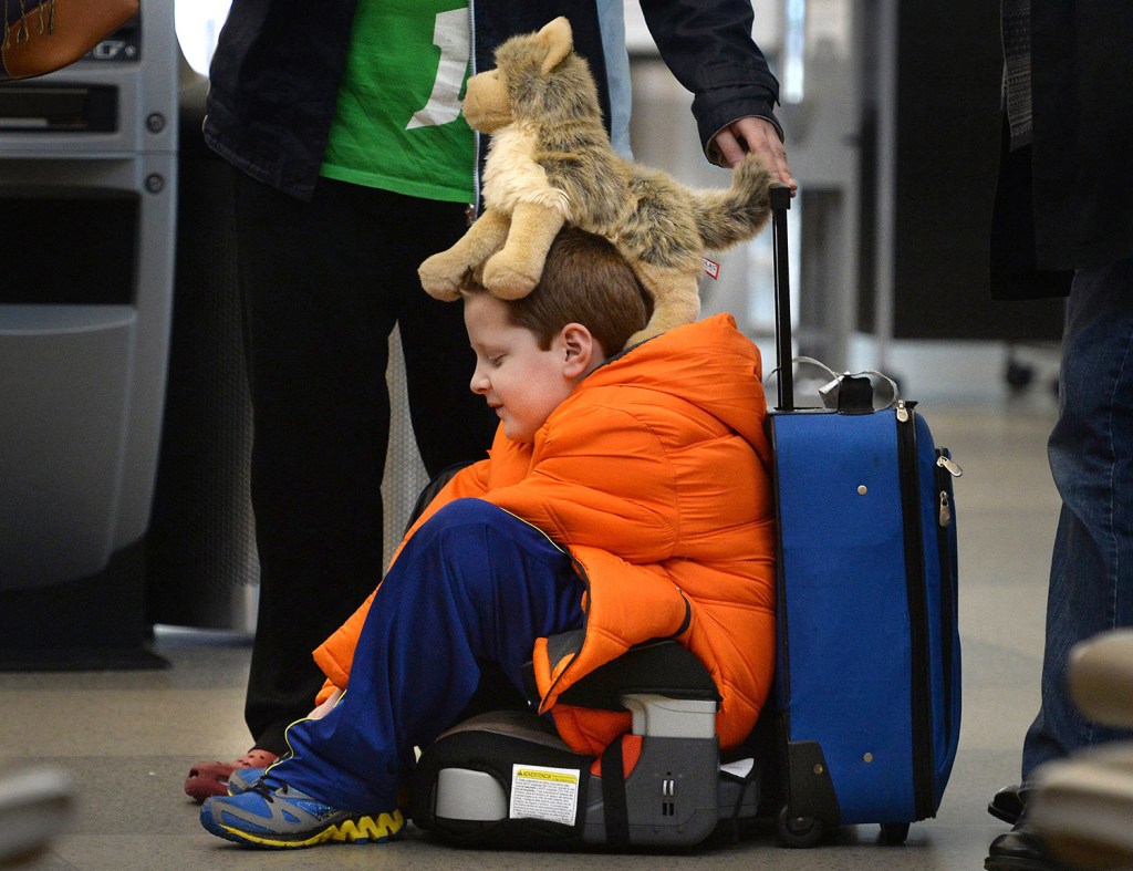 David Welborn, 7, sits in the lost luggage line at the Delta Airlines desk at RDU International Airport on Tuesday  With his trusty dog "Wolfbaby" perched on his head, he was with his mother and about 15 other people trying to find their bags after a  flight from Washington state. The Associated Press