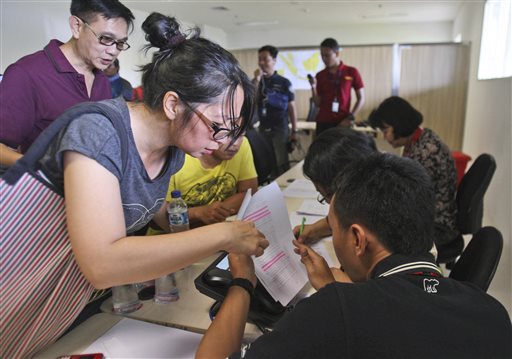 Relatives of the passengers onboard AirAsia flight QZ8501 check the plane's manifest at a crisis center set up at Juanda International Airport in Surabaya, East Java, Indonesia, on Sunday. The Associated Press
