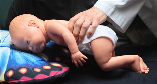Dr. Wendy Gunther uses a doll to demonstrate how an infant can die because of unsafe sleeping practices. The Associated Press
