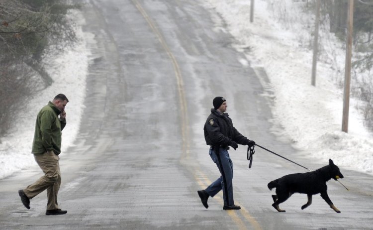Maine State Police Trooper G.J. Neagle accompanies his tracking dog and Augusta police Detective Chris Blodgett while searching Wednesday for a person reported to be in the woods between Farrington Elementary School and Cony High School in Augusta. Both schools were locked down for about an hour while police searched the woods. Nobody was found, according to police. 