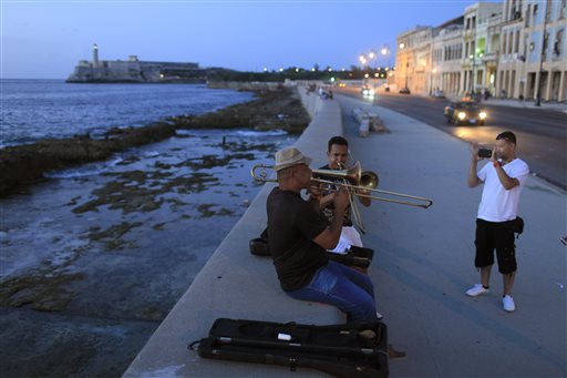 Musicians perform as a tourist from Colombia takes their picture along the Malecon in Havana, Cuba, in this July 8, 2013, photo. 