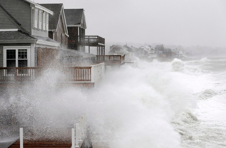 Waves splash against a seawall and onto houses along the Atlantic Coast on Tuesday in Scituate, Mass. The National Weather Service posted a flood watch for urban and poor drainage areas, and a coastal flood advisory for the midday high tide cycle.