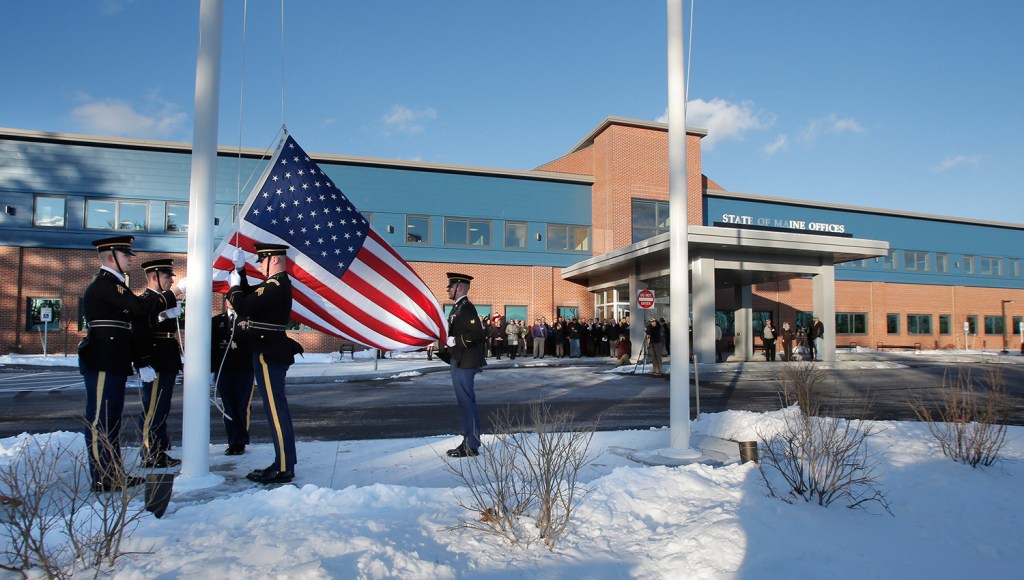 A military honor guard raises a flag Monday outside the new offices of the Department of Health and Human Services and Department of Labor in South Portland . The new building also houses regional offices of the Department of Veterans' Affairs.
