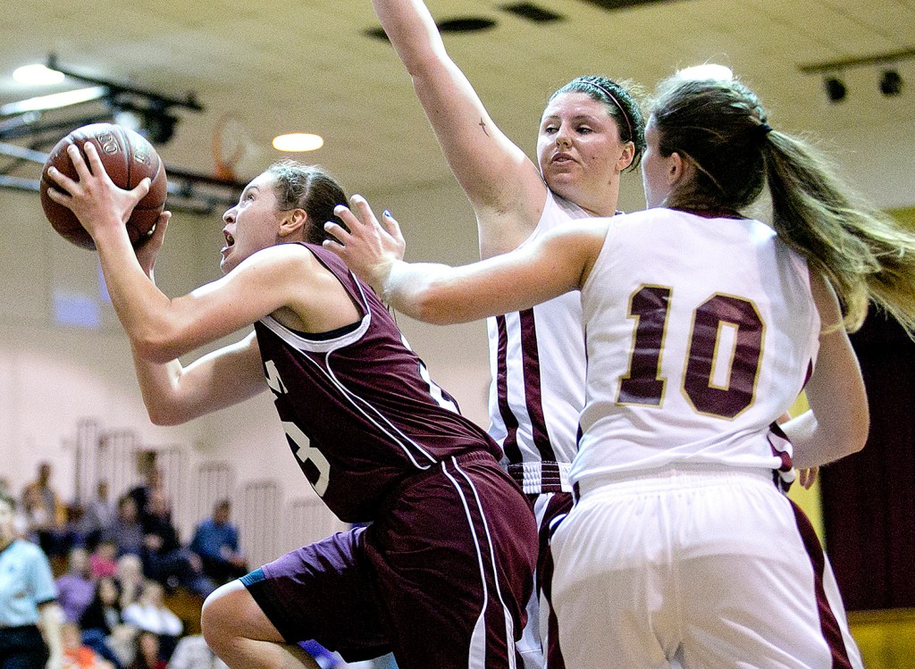 Gorham's Emily Esposito ducks under Thornton Academy's Victoria Lux and Kaitlyn McCrum for a late-game basket during a girls basketball game, Monday in Saco. Gabe Souza / Staff Photographer