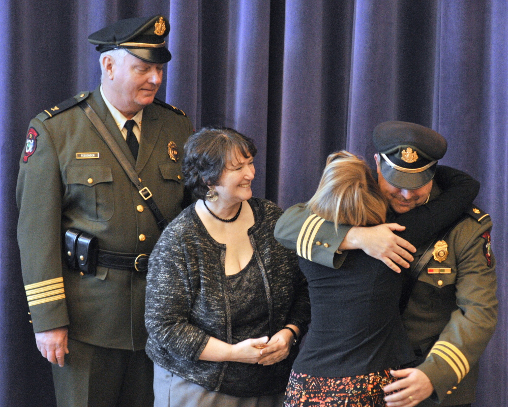 New Marine Patrol Col. Jon Cornish hugs his daughter Katrina Cornish after she pinned his badge on him during a change of command ceremony Friday at the Maine Criminal Justice Academy in Vassalboro. Retiring Marine Patrol Col. Joe Fessenden, left, and Cornish’s wife, Kim Cornish, also attended the ceremony.