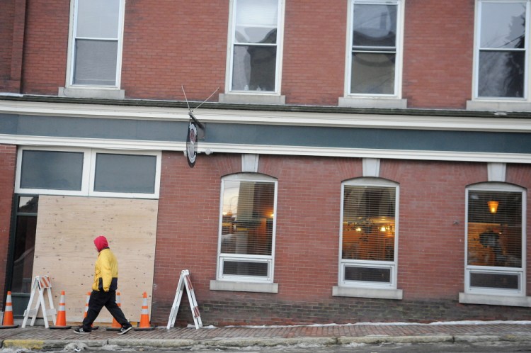 A man walks down Winthrop Street in Hallowell past the boarded up window at Hattie’s Chowder House on Monday. Andy Molloy / Kennebec Journal Staff Photographer