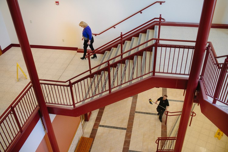 South Portland Superintendent Suzanne Godin walks down the stairs of the recently renovated South Portland High School on Friday while Aaron Bouchard mops the atrium. Godin spent Friday making sure all the furniture was in the right places.