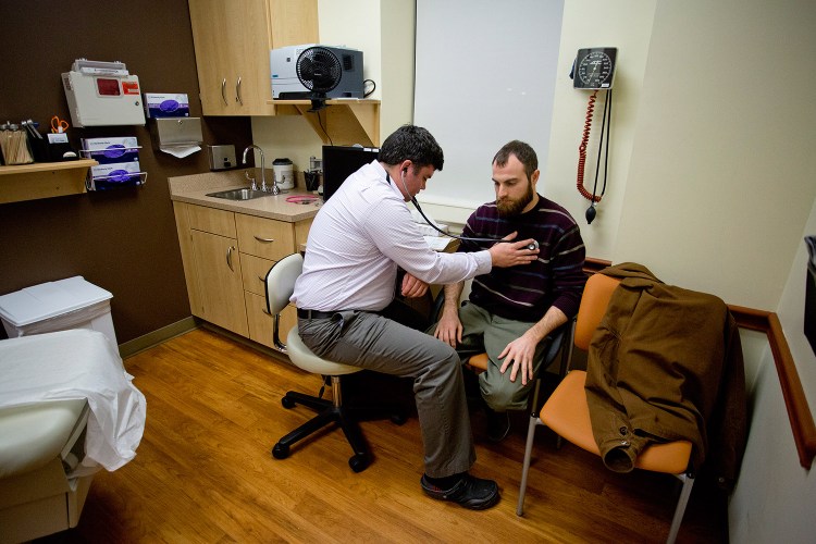 Dr. Brad Huot, a primary care physician at Martin's Point Health Care on Veranda Street in Portland, checks the heart rate of Tyson O'Keefe on Tuesday. The state announced that it will fill about an $8 million gap in federal funding to keep MaineCare reimbursements for physicians the same.