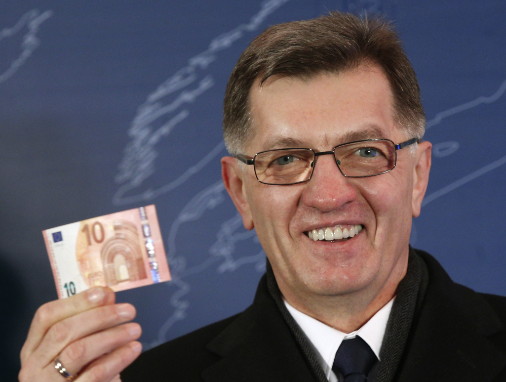 Lithuania’s Prime Minister Algirdas Butkevicius holds up a 10 Euro banknote that he withdrew from an ATM cash machine in Vilnius, Lithuania, early Thursday. 