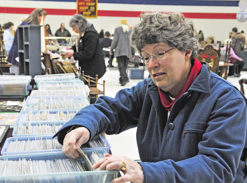 Mary Saunders flips through postcards Thursday at the 24th annual Augusta Armory Antiques Show. “I enjoy looking at everything,” she said.