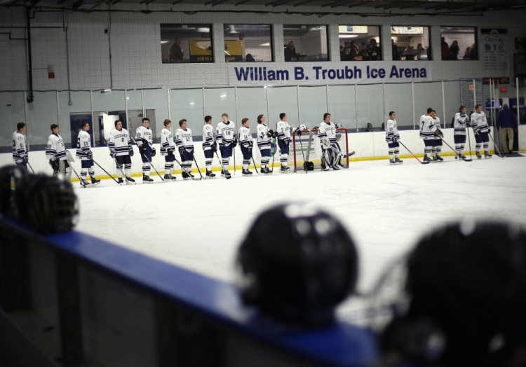 The combined Portland High-Deering High boys’ hockey team lines up Thursday before the start of the team’s City Cup game against Cheverus, in front of a banner carrying the new name of what was once the Portland Ice Arena. The City Cup series was created to raise hockey’s profile in Portland and raise money for the Portland Middle School Hockey Association.