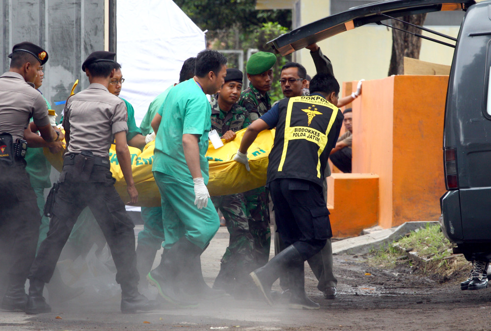 Indonesian police, military and medical workers carry a body bag holding a victim of AirAsia Flight 8501 for identification at Bhayangkara Police Hospital in Surabaya, Indonesia, on Saturday. After nearly a week of searching for victims, rescue teams had their most successful day yet, more than tripling the number of bodies pulled from the Java Sea, some still strapped to their seats.