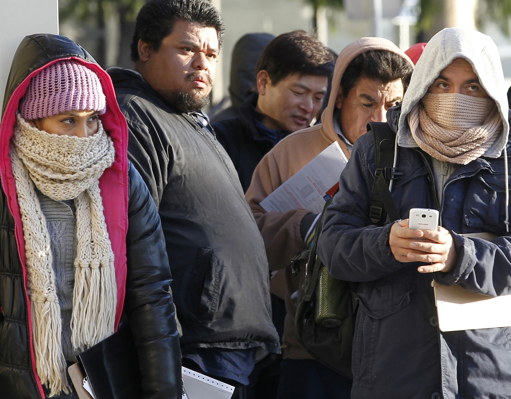 Immigrants brave the cold weather as they line up outside a California Department of Motor Vehicles office to register for driver’s licenses in Stanton, Calif., Friday. The process starts with a written exam, which about half will fail, officials said.