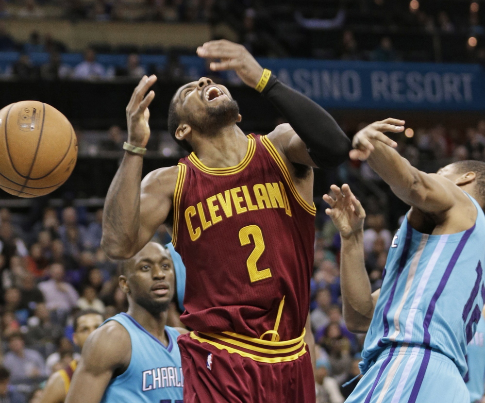 Cleveland’s Kyrie Irving is fouled by Charlotte’s  Gary Neal during the second half of Friday’s game in Charlotte. The Cavaliers won despite being without LeBron James.