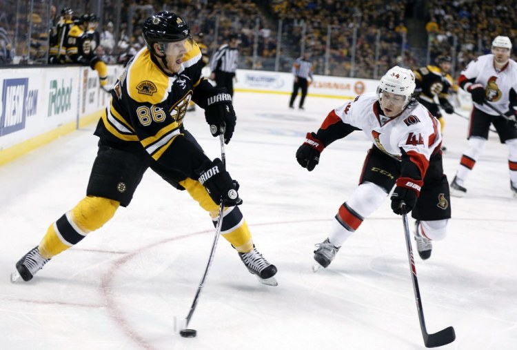 Boston Bruins’ Kevan Miller takes a shot as Ottawa Senators’ Jean-Gabriel Pageau defends during the second period of an NHL hockey game in Boston, Saturday, Jan. 3, 2015.