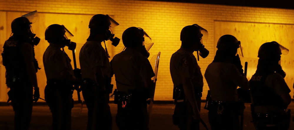 Police wait to advance after tear gas was used to disperse a crowd during a protest on Aug. 17 in Ferguson, Mo., six days after Michael Brown was killed by a police officer. Many in the Ferguson area are working to heal the wounds caused by the shooting death and the rioting in August and again in November after a grand jury decided not to indict the officer.
The Associated Press