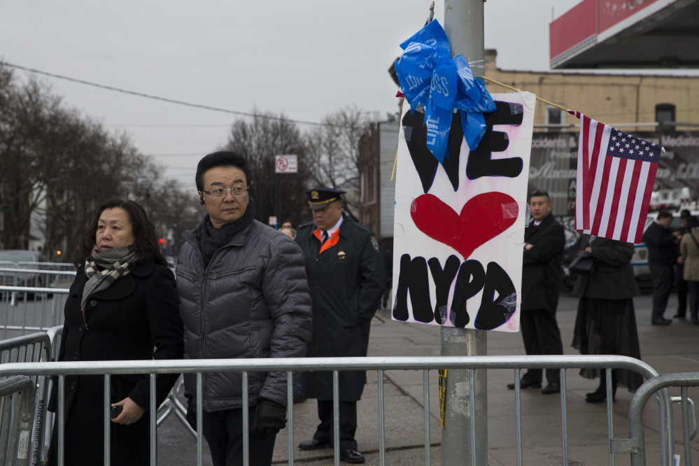 Pedestrians pause outside the funeral of New York Police Department officer Wenjian Liu at Aievoli Funeral Home, on Sunday, in the Brooklyn. Liu and his partner, officer Rafael Ramos, were killed Dec. 20 as they sat in their patrol car on a Brooklyn street. The shooter, Ismaaiyl Brinsley, later killed himself.