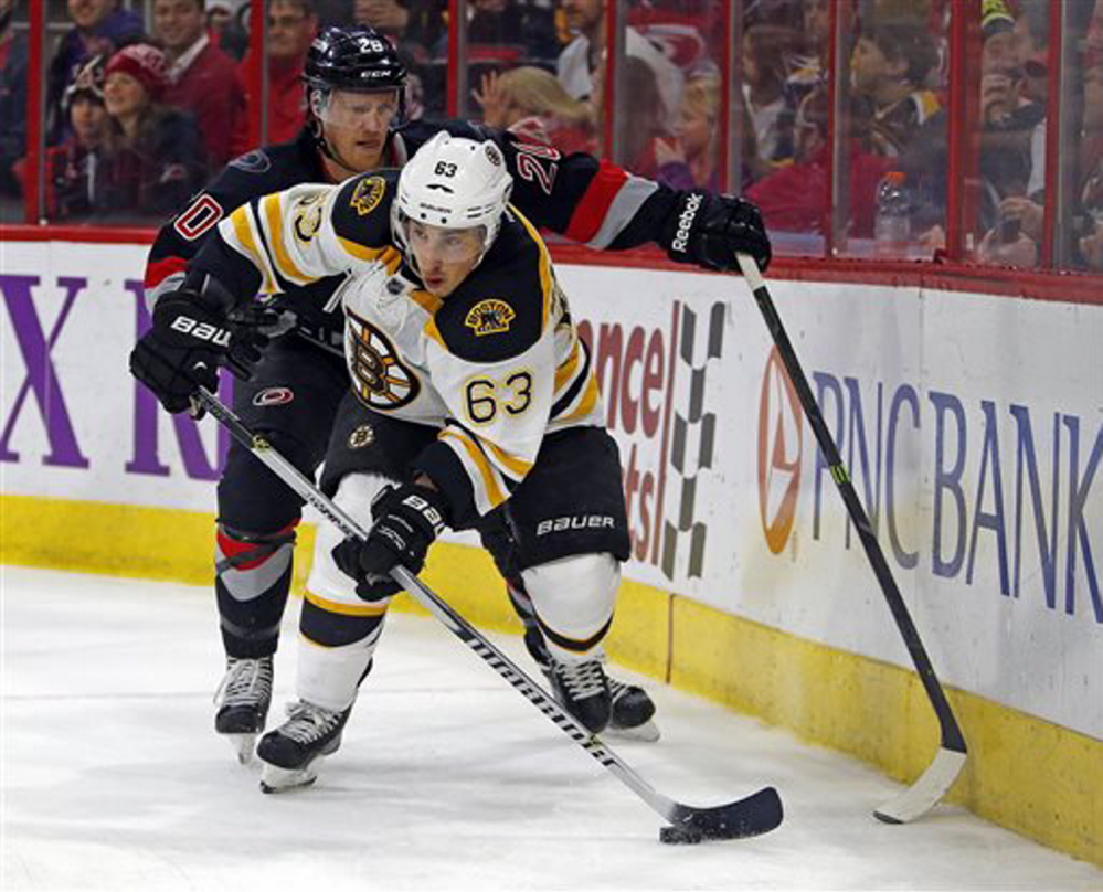 Boston Bruins’ Brad Marchand battles with Carolina’s Riley Nash in Sunday’s game at Raleigh, N.C. The Hurricanes won 2-1 in a shootout.