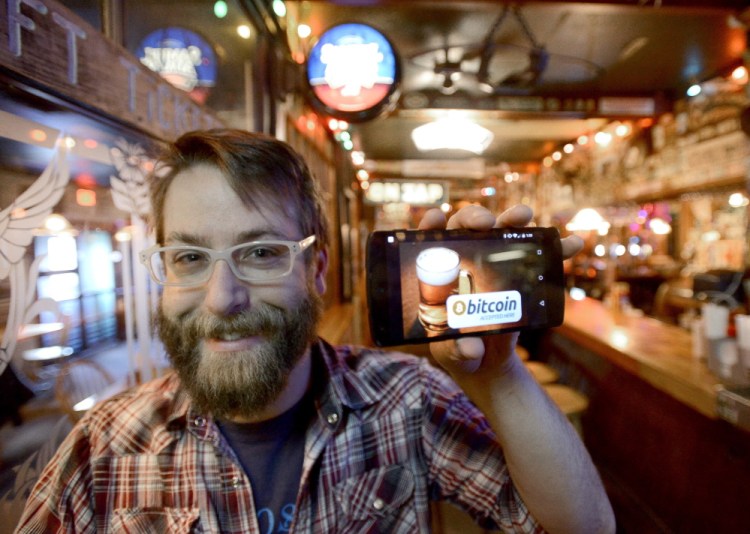 Dave Foster, media marketing manager at The Great Lost Bear in Portland, holds up his mobile phone displaying a bitcoin app that can be used for payment at his restaurant.