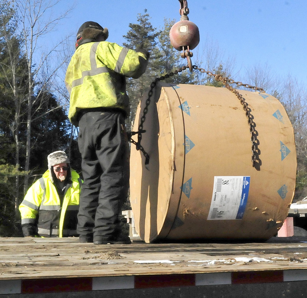 Workers on Monday load rolls of paper after using a crane to unload a tractor-trailer that slid and overturned on the northbound lane of I-95 in Sidney on Sunday night. Traffic was detoured from exit 113 to exit 120.