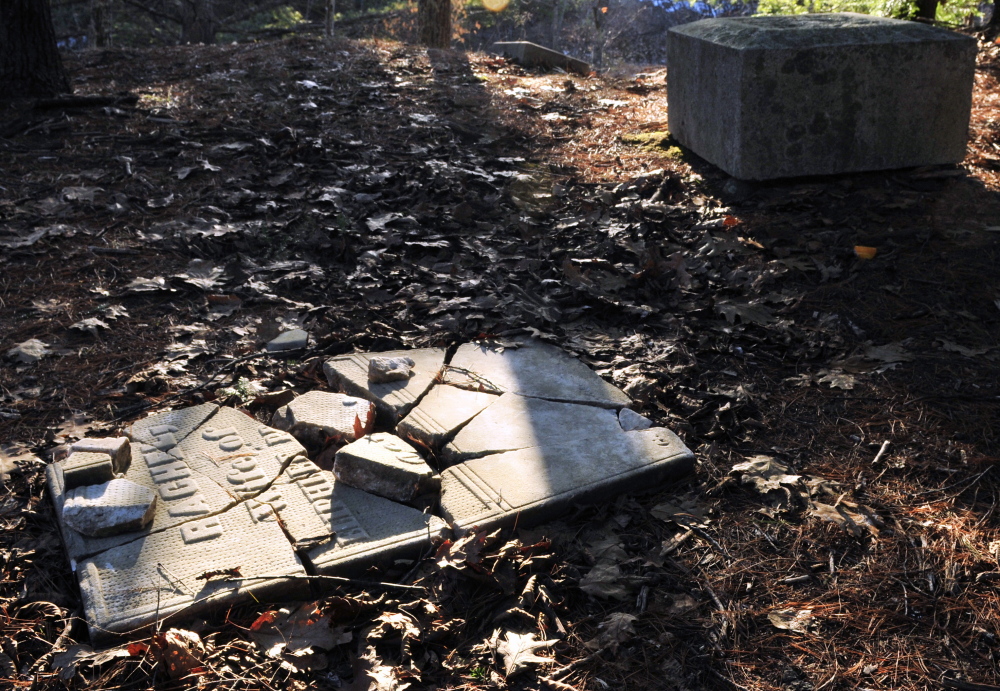 A cracked tombstone on the ground and the base of a four-sided obelisk are in the Edgecomb cemetery in Gardiner.