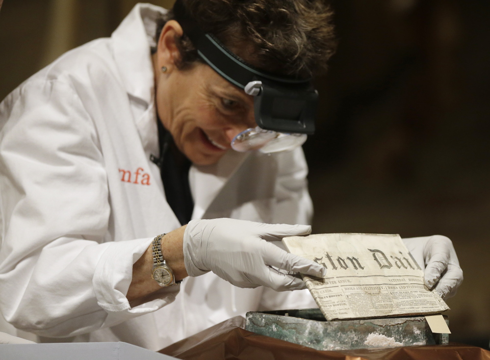 Museum of Fine Arts Boston Head of Objects Conservation Pam Hatchfield removes a folded 19th century newspaper from the time capsule.
