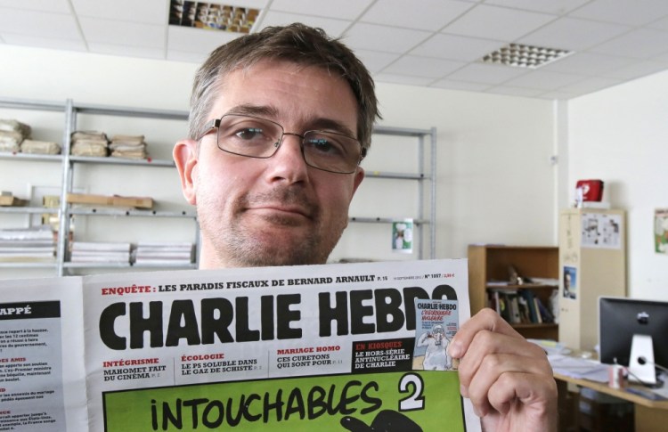 In this Sept.19, 2012 file photo, Charb , the publishing director of the satyric weekly Charlie Hebdo, displays the front page of the newspaper as he poses for photographers in Paris.