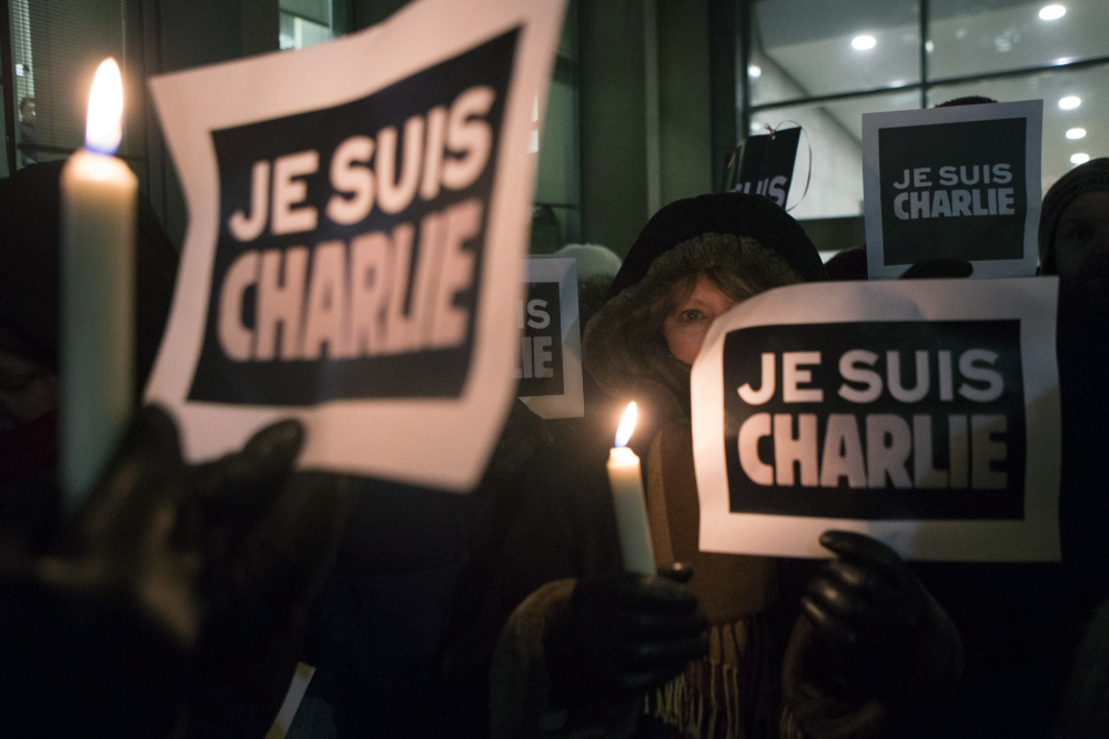 People gather outside the French Consulate in Toronto on Wednesday in response to the shootings earlier in the day at Charlie Hebdo Magazine in Paris. The writing on the signs reads “I am Charlie.”