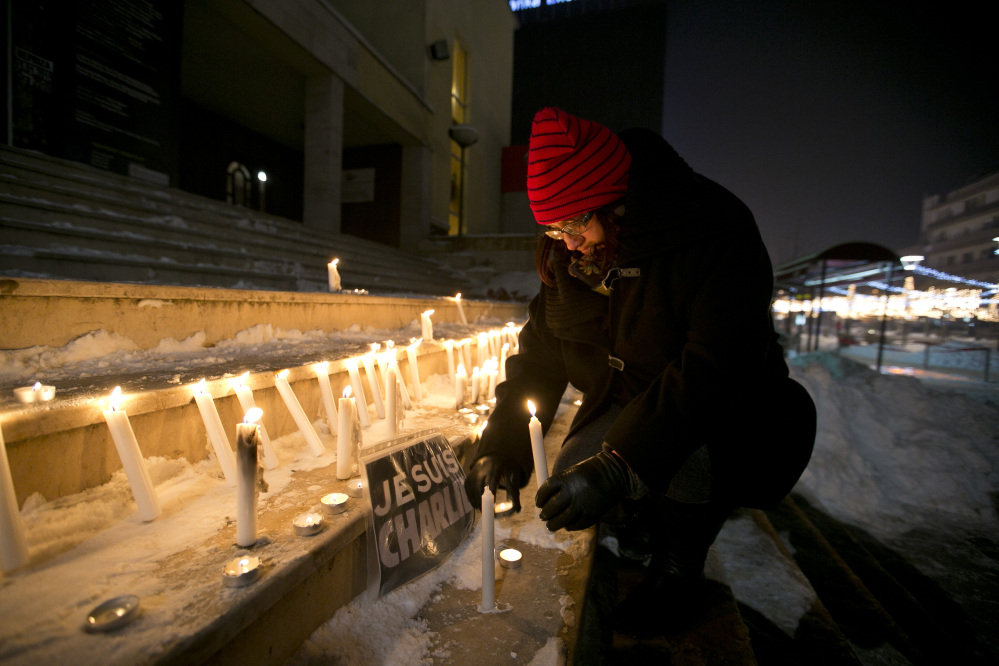 A woman in Pristina, Kosovo, lights a candle near a sign that reads in French “I am Charlie” during a demonstration in solidarity with those killed in Wednesday’s attack at the Paris offices of Charlie Hebdo.