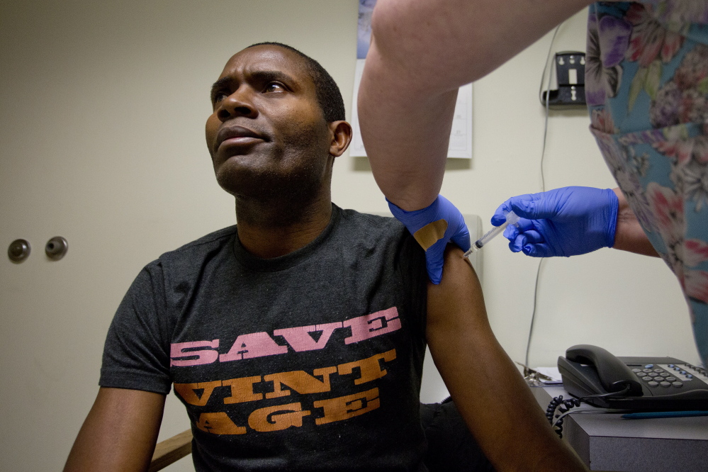 Susan Huff, vaccines manager at the Portland Community Health Center, administers a flu shot Wednesday to patient Bruno Mbango Enyaka, 41, at the Park Street clinic. No flu cases have been reported at the center so far this season.