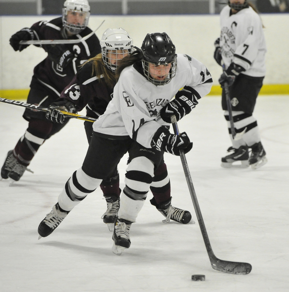 Kate Ginder of Cape Elizabeth/Waynflete/South Portland pushes the puck ahead of Greely’s Faith Price in Wednesday’s game. Greely improved to 10-2.