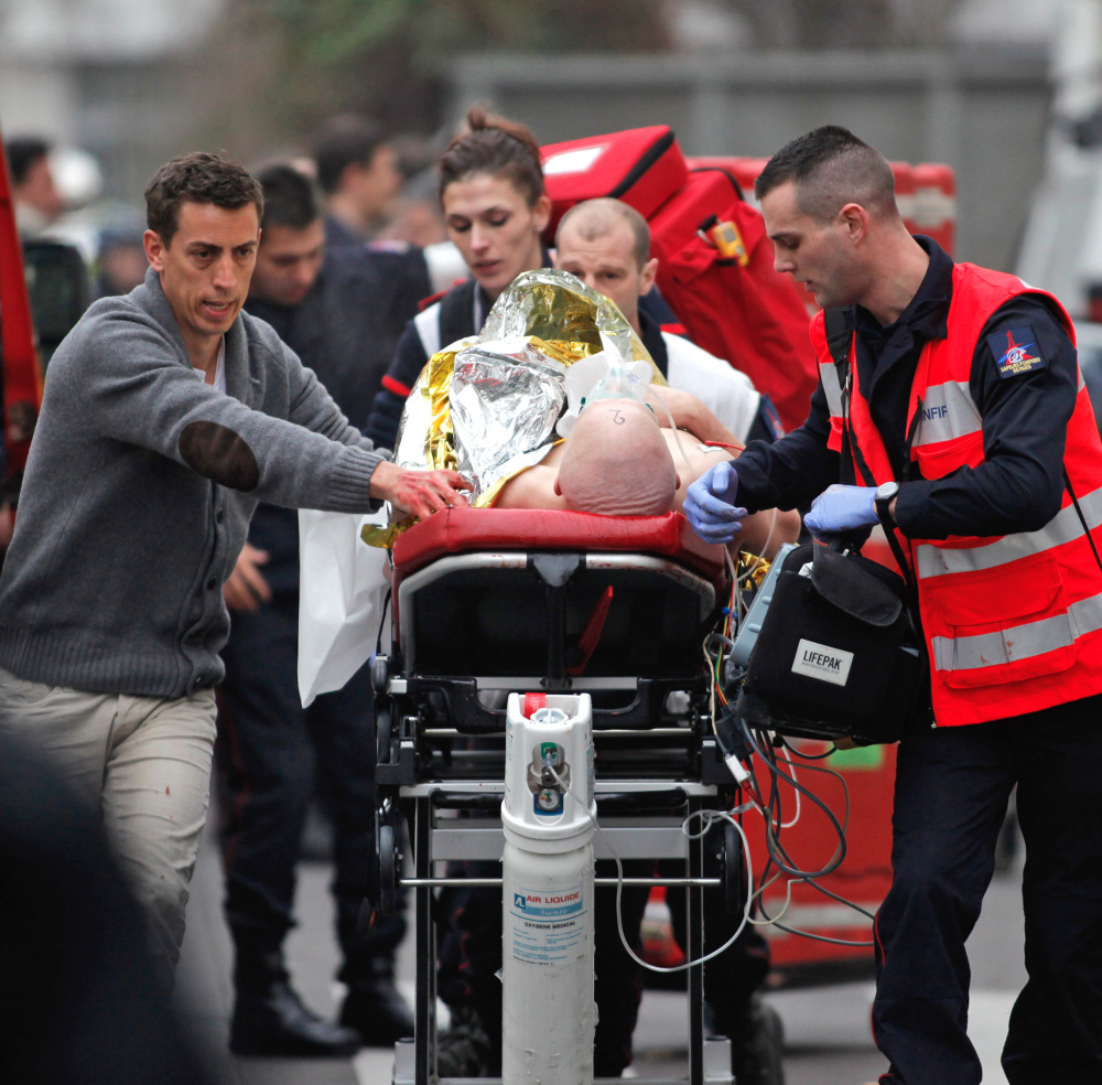 An injured person is transported to an ambulance after the shooting at the French satirical newspaper Charlie Hebdo’s office, in Paris, Wednesday.
