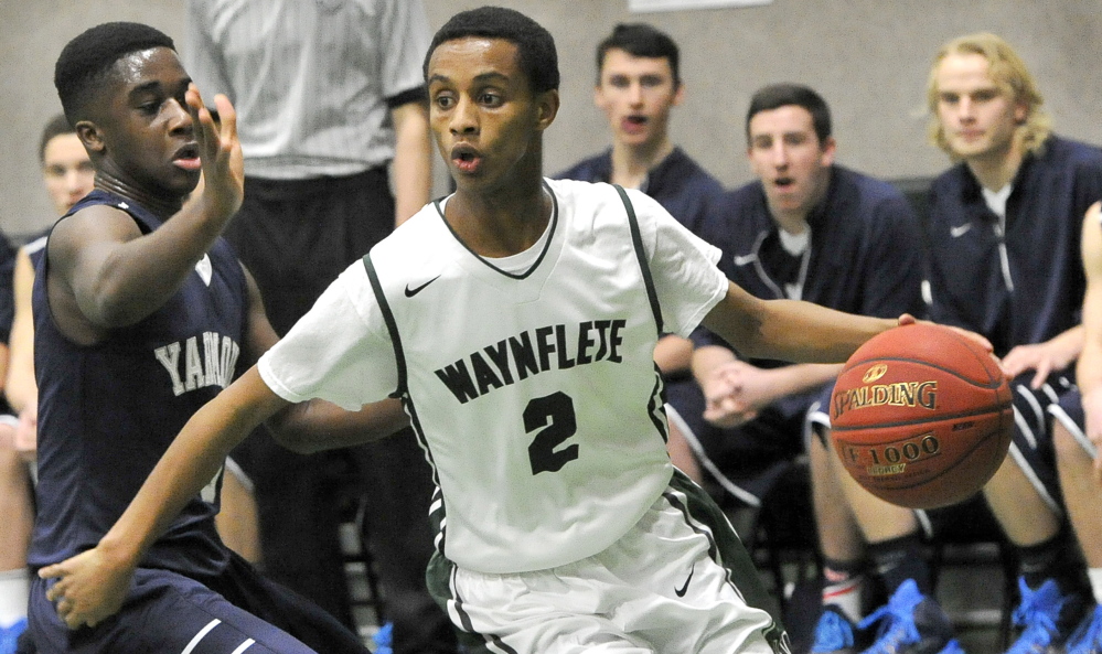 Waynflete’s Abel Alemayo drives around Yarmouth’s Musseit M’Bareck, left, during the Flyers’ 53-43 win at  home Tuesday.