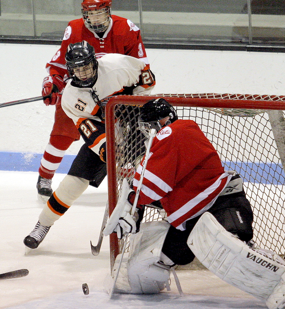 South Portland goaltender Joe Grant turns aside a shot while Brunswick’s Jacob Towle eyes the rebound during Thursday night’s game, won by the host Dragons 5-2.