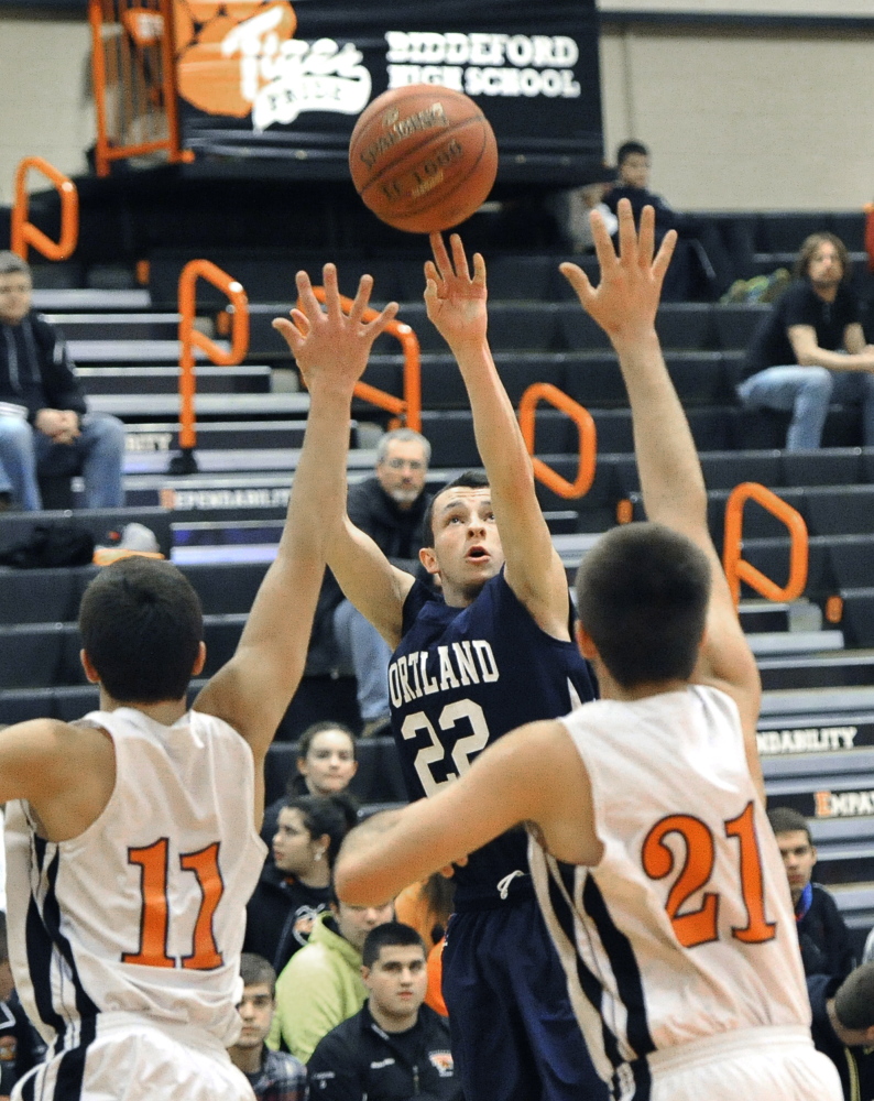 Liam Densmore, who finished with 17 points for Portland, lofts a jumper between Patrick Pearl, left, and Jason Vadnais of Biddeford during Portland’s 67-33 victory Friday night at Biddeford High.