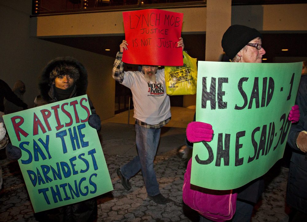 A Bill Cosby supporter (center) marches among protesters demonstrating outside the Hamilton Place Theatre before a performance by Cosby in Hamilton, Ont., on Friday night.