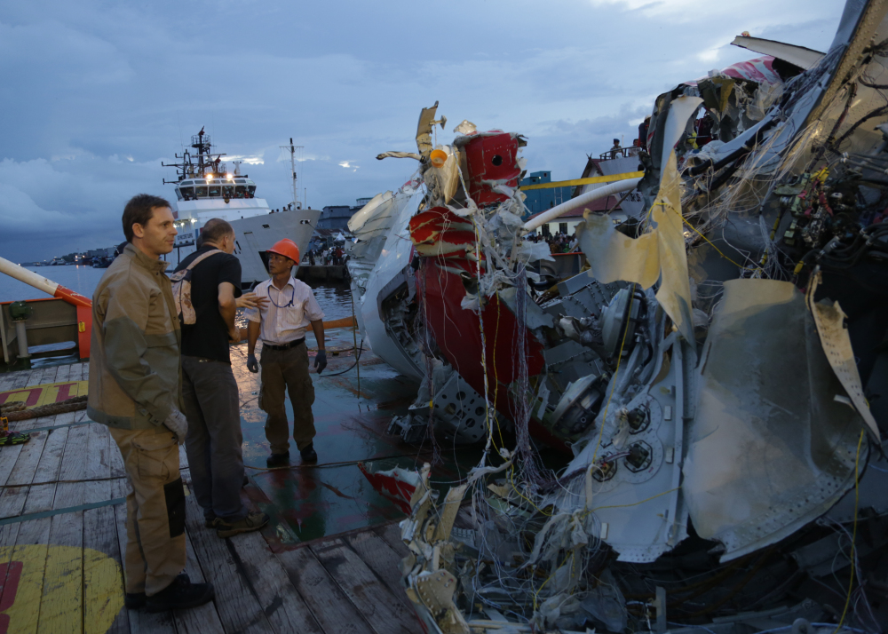 An Indonesian member of  National Transportation Safety Board talk with a foreign investigator  near part of the tail of AirAsia Flight 8501  on the deck of rescue ship Crest Onyx   at Kumai port in Pangkalan Bun,Sunday.